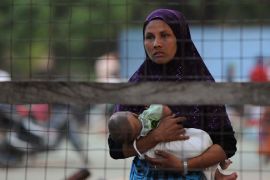 Meiktila, -, MYANMAR : A Muslim woman holds her baby as she looks out from a temporary relief camp in riot-hit Meiktila on March 23, 2013. Troops patrolled the streets of a central Myanmar town on March 23 after Buddhist-Muslim