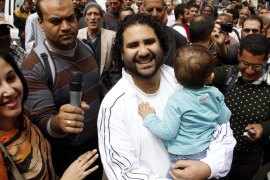 epa03641335 Egyptian activist Alaa Abdel-Fatah (C), carrying his child, arrives at Prosecutor-General's office for interrogation over alleged accusations of inciting violence, in Cairo, Egypt, 26 March 2013. Hundreds gathered in front of Prosecutor-General's office to protest against the summoning of five leading opposition activists over alleged accusations of inciting violence. The activists are accused of inciting violence against the Muslim Brotherhood during clashes on 22 March, where more than 100 people were injured. EPA/STR