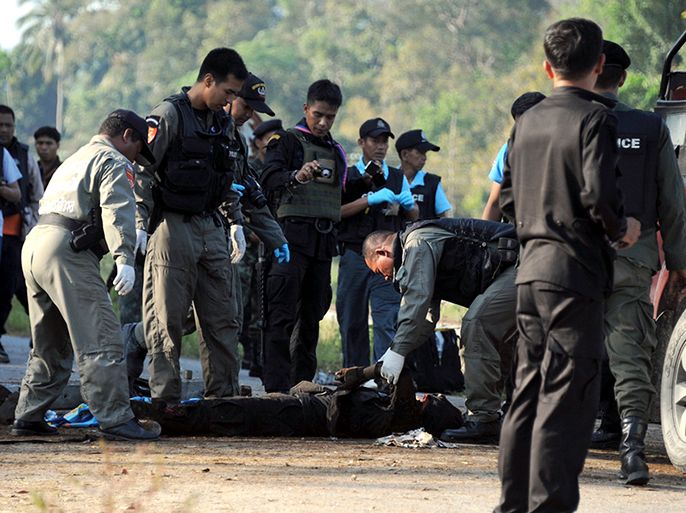 epa03643207 Thai forensic policemen and members of a bomb disposal team inspect a body of a paramilitary ranger who was killed at a bomb blast scene on a road in Cho-airong district of Narathiwat province, southern Thailand, 28 March 2013. Thailand and a Muslim rebel group started peace negotiations in Malaysia as a bombing by suspected Islamist militants in a Thai province plagued by the insurgency killed three people. Suspected separatist detonated a roadside bomb attack a unit of Thai paramilitaries while they were on foot patrol. The bomb killed three soldiers and injured others five, police said. More than 5,300 people have been killed in the conflict in the majority-Muslim provinces of Thailand, which are under emergency law. EPA/PADUNG WANNALAK