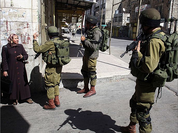 Israeli soldiers stop a Palestinian woman from reaching her home as security checks increase during the visit of Israeli Jews to the tomb of Othniel Ben Kenaz, considered holy by the Jewish faith, in the Palestinian side of the city of Hebron, on March 27, 2013. Religious Jews worldwide eat matzoth during the eight-day Pesach holiday that commemorates the Israelis' exodus from Egypt some 3,500 years ago and their ancestors' plight by refraining from eating leavened food products. AFP PHOTO/HAZEM BADER