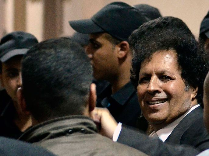 EGY029 - Cairo, -, EGYPT : Libyan Ahmed Kadhaf al-Damm (R), cousin of ousted Libyan leader Moamer Kadhafi, smiles as he escorted by policemen into the office of the Egyptian general prosecutor after being arrested in Cairo March 19, 2013. Egyptian police arrested Kadhaf al-Damm, who is wanted in Libya for his role in the regime of the slain Libyan strongman, Egyptian state media reported. AFP PHOTO / MOHAMED EL-SHAHED