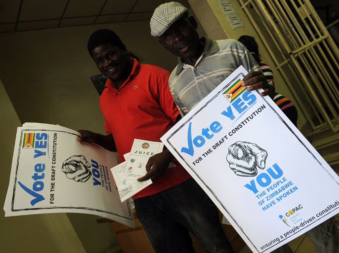 ZIMBABWE : Men hold up posters calling on Zimbabweans to vote yes for the constitutional referendum to be held in country over the weekendto vote for the new constitution in Harare on March 14, 2013