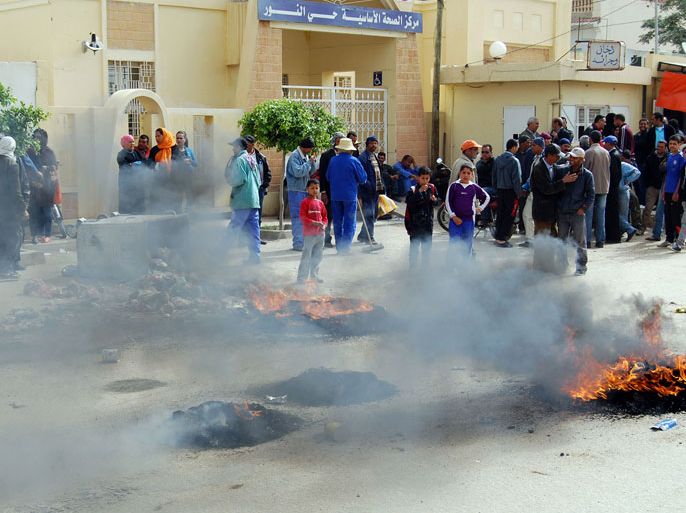 Tunisian protesters stand next to burning tyres set on fire to block a road in the centre of Kasserine on April 30, 2013 during a protest in support of security forces and to demand better equipment for the military to detect land mines and protect themselves. The protest came as land mines wounded six soldiers and police in western Tunisia as security forces continued a search for "terrorists" that has already caused casualties, the interior ministry said