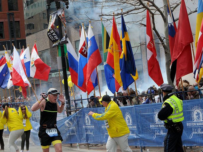 epa03664483 A picture made available on 16 April 2013 shows Police and runners react after two explosions at the Boston Marathon finish area, Boston, Massachusetts, USA, 15 April 2013. Three people were killed and over 100 were injured when two bombs exploded on 15 April 2013 at the finish line of the marathon. EPA/MetroWest Daily News/Ken McGagh MANDATORY CREDIT EDITORIAL USE ONLY/NO SALES
