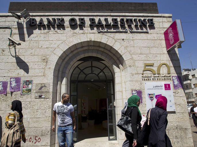 epa03393644 Palestinian passing a branch of the Bank of Palestine in the West Bank town of Ramallah, 11 September 2012, on a day when many marched in protest over the rising cot of living. Palestinians took to the streets to protest against the increasing cost of living in the West Bank. Scores of demonstrators in Ramallah were calling for Salam Fayyad, the prime minister of the Palestinian Authority 's West Bank government, to quit. Fayyad, an internationally-respected economist, has become the focus of the anger against the rising prices. EPA/JIM HOLLANDER