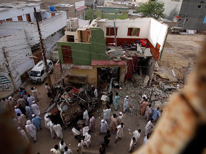 People stand outside a damaged Awani National Party (ANP) election campaign office after Friday night's bomb explosion, in Karachi April 27,2013. At least 10 people were killed and dozens injured in an explosion late April 26, 2013 targeting an election office of the Awami National Party (ANP) in Karachi. REUTERS/Athar Hussain (PAKISTAN - Tags: POLITICS CIVIL UNREST ELECTIONS CRIME LAW)