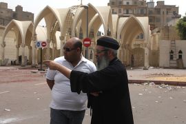 A Coptic Christian priest estimates the damage near the gate inside Cairo's main Coptic cathedral after Sunday's clashes with Muslims in Cairo, April 8, 2013. After days of fighting at the cathedral and a town outside Cairo killing eight - the worst sectarian strife since Islamist President Mohamed Mursi was elected in June - many Copts now question whether they have a future in Egypt. Picture taken April 8, 2013. REUTERS/Asmaa Waguih (EGYPT - Tags: RELIGION POLITICS CIVIL UNREST)