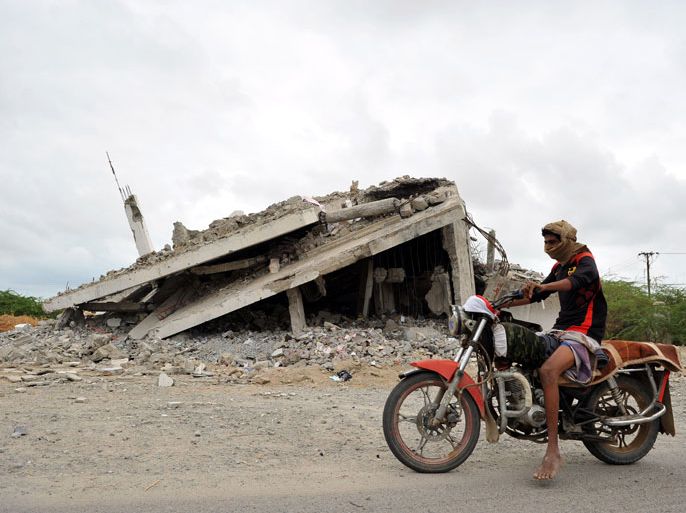 epa03595679 A Yemeni man riding a motorbike drives past a building destroyed during a US drones-backed military campaign against al-Qaeda militants in the southern town of Zinjibar, Yemen, 22 February 2013. US drone strikes against suspected al-Qaeda militants are reportedly frequent in Yemen, home of the Al-Qaeda in the Arabian Peninsula (AQAP), described by the US as the most active and dangerous branch of the terrorist network. EPA/YAHYA ARHAB