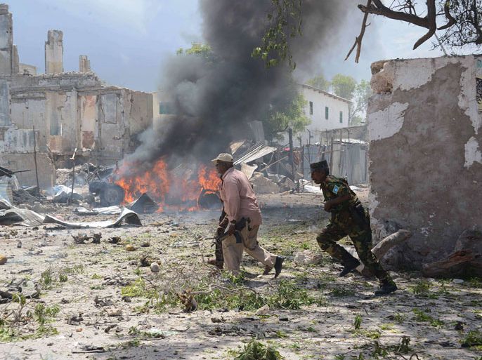 Somali police run for cover April 14, 2013 after gunmen wearing suicide vests stormed the main court complex in Mogadishu, killing at least five people before holing themselves up as Somali and African forces surrounded the building. Several people were wounded minutes later when a remote-detonated car bomb went off as a Turkish aid convoy drove by near the airport, in some of the worst violence to hit Mogadishu in months. AFP PHOTO / MOHAMED ABDIWAHAB
