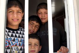 AMM23 - Zarqa, -, JORDAN : Syrian refugee children look out the window of a portacabin at the newly built UAE funded Mrigb al-Fuhud refugee camp, 20 kilometres east of the Jordanian city of Zarqa, on April 15, 2013. The seven-million-dinar ($9.8-million) camp which has 750 caravans, a hospital, and a school and can take up to 5,500 people, was paid for by the United Arab Emirates. AFP PHOTO/STR