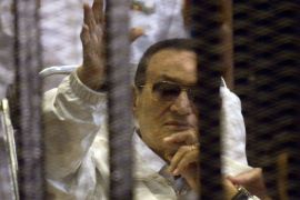EGYPT : Ousted Egyptian president Hosni Mubarak waves as he sits behind bars during a hearing in his retrial at the Police Academy in Cairo on April 13, 2013. The judge in the retrial of Mubarak recused himself, in a chaotic opening hearing that lasted just seconds and saw a proud and combative Mubarak smile and wave in the dock.
