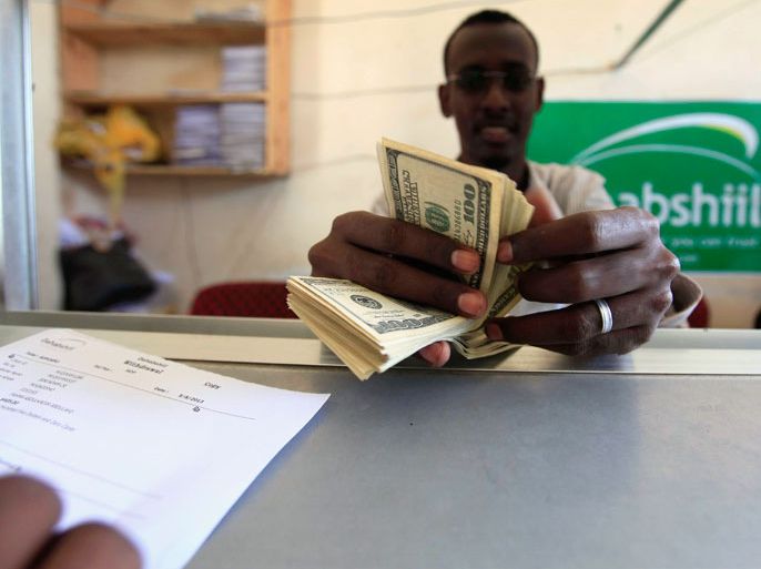 A worker counts U.S. dollars as he serve a customers at a Dahabshiil money transfer office in "Kilometer Five" street of Soobe village, southern Mogadishu, May 8, 2013. Somalia's government must lure more investors to drive the private economy because business owners have an interest in cementing fragile security gains, the chief executive of Somalia's biggest financial firm said. To match Interview SOMALIA-BUSINESS/ REUTERS/Feisal Omar (SOMALIA - Tags: BUSINESS SOCIETY)