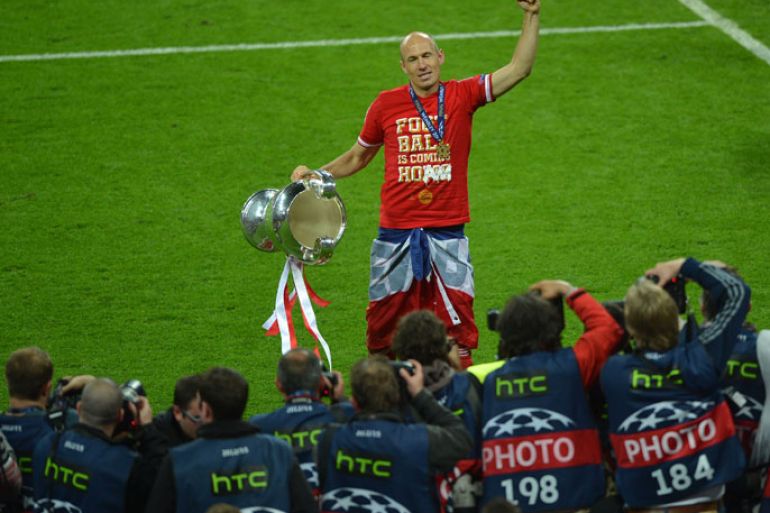 Bayern Munich's Dutch midfielder Arjen Robben celebrates with the trophy in front of photographers on the pitch after their victory in the UEFA Champions League final football match between Borussia Dortmund and Bayern Munich at Wembley Stadium in London on May 25, 2013, Bayern Munich won the game 2-1 AFP PHOTO / PATRIK STOLLARZ