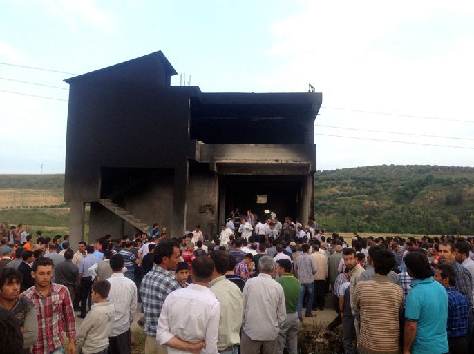 People gather in front of an illegal fuel depot on May 17, 2013, after suspects set ablaze the depot located in the basement of a three-storey building in a small village near Turkey's border with Syria, triggering a strong explosion that killed at least ten people and wounded nine others. Among the wounded were three suspected smugglers as well as several security officers, Anatolia news agency reported. AFP