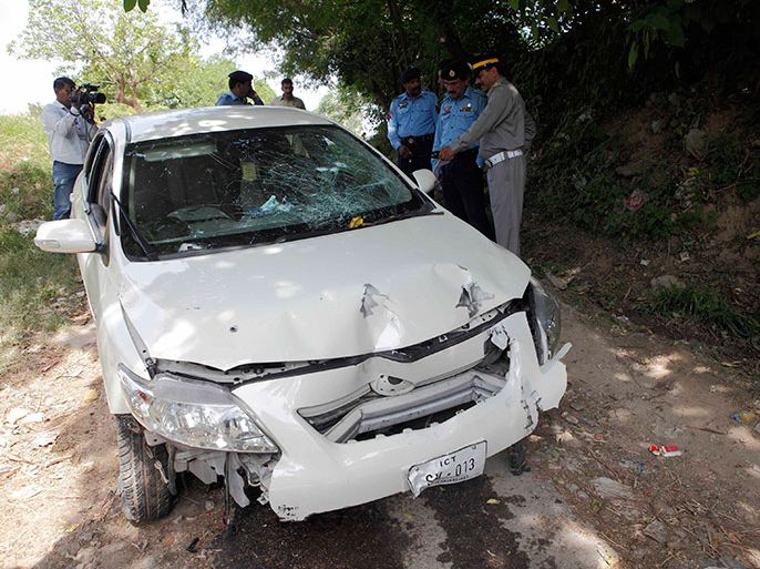 Security officials inspect the damaged car, which prosecutor Chaudhry Zulfikar was travelling in, when he came under attack by unidentified gunmen, in Islamabad May 3, 2013. Zulfikar, the prosecutor investigating the 2007 assassination of former Pakistani Prime Minister Benazir Bhutto, one of the most shocking events in Pakistan's turbulent history, was shot dead on Friday, police sources said. Gunmen on a motorcycle pumped 12 bullets into Zulfikar as he left his home in Islamabad, the sources said.     REUTERS/Mian Khursheed    (PAKISTAN - Tags: POLITICS CIVIL UNREST CRIME LAW)