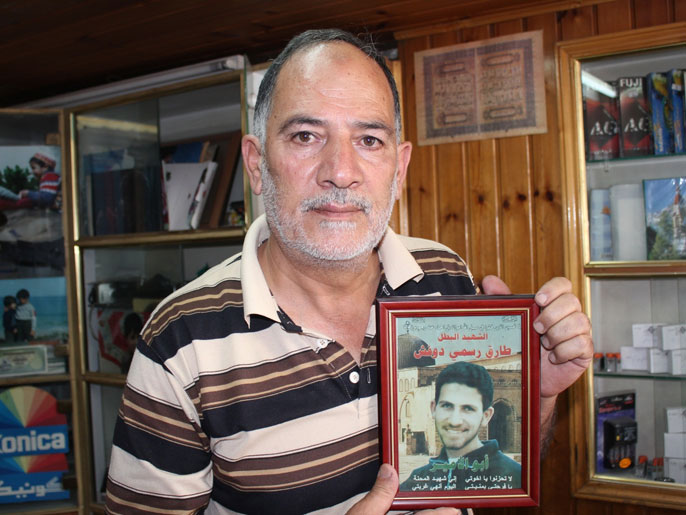 والد الشهيد طارق دوفش يحمل صورة ابنه الذي استشهد عام 2002 (الجزيرة نت)