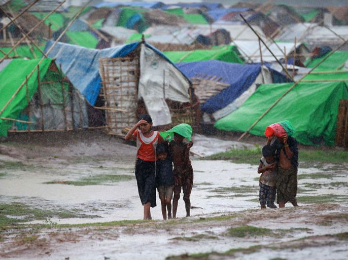 Muslim Rohingya kids walk in front of their tent as rain falls at Mansi Internally Displaced Persons (IDP) camp in Sittwe on May 14, 2013. Boats carrying scores of Rohingya Muslims fleeing a cyclone have capsized off Myanmar's coast, the UN said on May 14, heightening fears over the storm which threatens camps for tens of thousands of displaced people