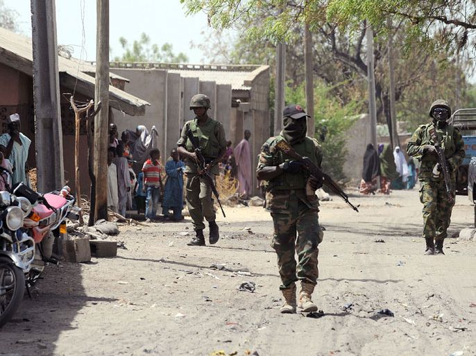 7 - Baga, -, NIGERIA : (FILES) This picture taken on April 30, 2013 shows Nigerian troops patrolling in the streets of the remote northeast town of Baga, Borno State. Nigeria's military said on May 16, 2013 that it was ready to launch air strikes against Boko Haram Islamists as several thousand troops moved to the remote northeast to retake territory seized by the insurgents. A force of "several thousand" soldiers along with fighter jets and helicopter gunships have been deployed for the offensive in Borno, Yobe and Adamawa state, he added. AFP PHOTO/PIUS UTOMI EKPEI