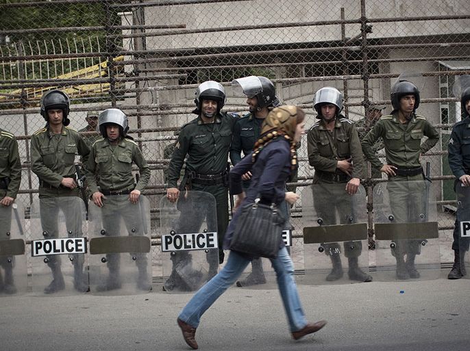 An Iranian woman rushes past riot police in Tehran in April 2011. (Behrouz Mehri/AFP/Getty Images)