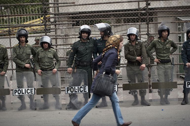 An Iranian woman rushes past riot police in Tehran in April 2011. (Behrouz Mehri/AFP/Getty Images)