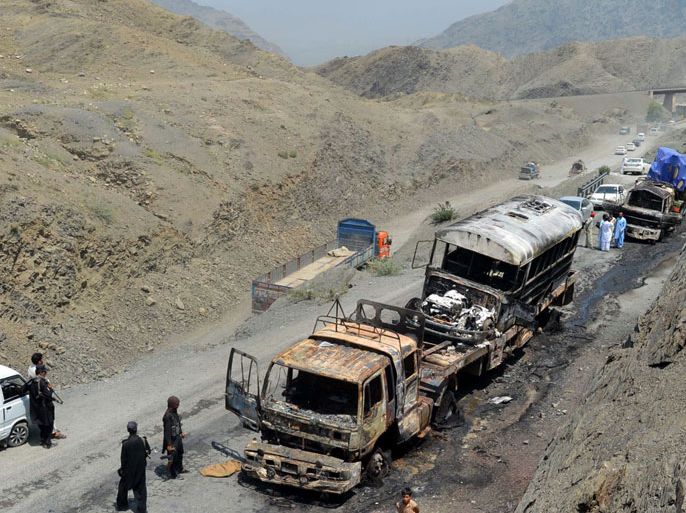 : Pakistani policemen stand alongside torched NATO supply trucks after an attack by armed militants in Khyber district on June 10, 2013. Militants attacked NATO supply trucks in northwest Pakistan with guns and mortars on June 10, setting vehicles ablaze and killing at least six people, officials said. AFP PHOTO / A. MAJEED
