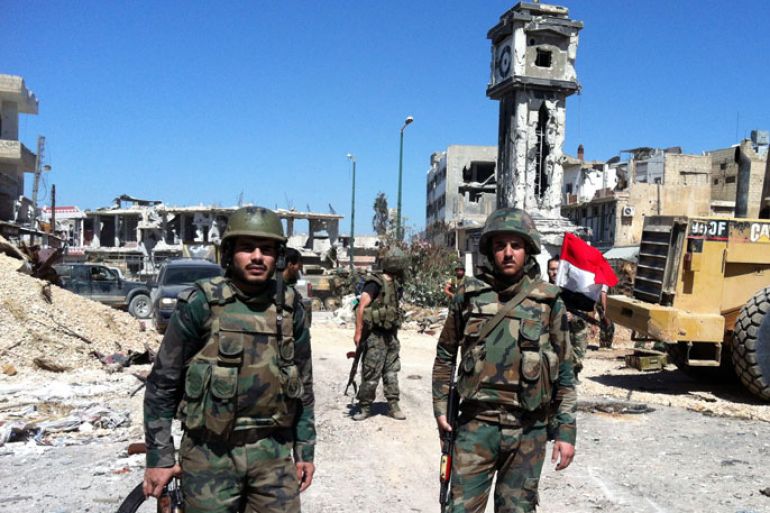 QUSAYR, -, SYRIA : Syrian government soldiers stand in front of the clock tower flying the national flag in the main square of the city of Qusayr, in Syria's central Homs province, on June 5, 2013, after the army claimed it had seized total control of it and the surrounding region. Syria's rebels conceded they had lost the battle for the strategic town of Qusayr which was vital for the opposition as it was their principal transit point for weapons and fighters from neighbouring Lebanon. AFP PHOTO / STR