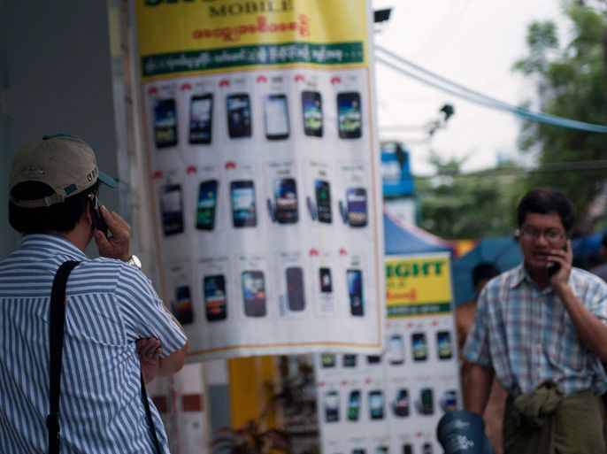 , -, MYANMAR : People speaks on mobile phones in Yangon on June 27, 2013. Myanmar on June 27 awarded telecom licences to Norway's Telenor and Qatari firm Ooredoo, the government committee in charge of the bids said, opening up one of the world's last virtually untapped mobile phone markets. AFP PHOTO