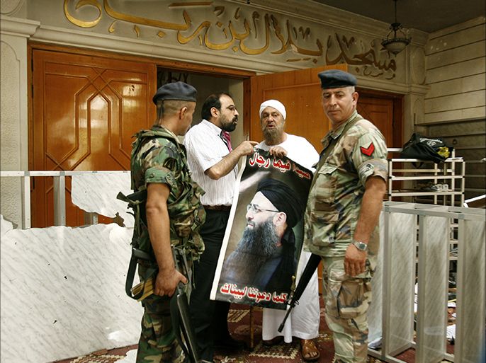 Supporters of radical Sunni cleric Sheikh Ahmad al-Assir carry a poster bearing his portrait next to members of the Lebanese Army at the entrance of the Bilal bin Rabah mosque in the Abra district of the southern city of Sidon on June 29, 2013. The fighting in Abra outside Sidon was the worst in Lebanon since the outbreak of conflict in neighbouring Syria 27 months ago deepened sectarian tensions. AFP PHOTO/MAHMOUD ZAYYAT