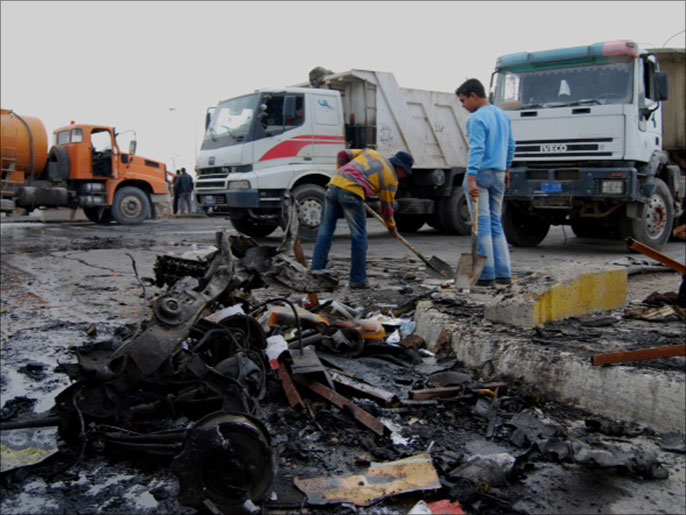 تنظيف وإزالة مخلفات تفجير سابق في إحدى مناطق بغداد (الجزيرة نت)