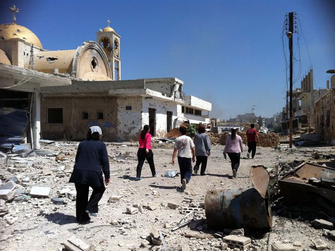 A picture taken on June 6, 2013 shows people walking past a damaged church in Qusayr in Syria's central Homs province. Syrian soldiers bombarded a village where rebels and civilians fled to after being routed the previous day from the strategic border town of Qusayr, the Syrian Observatory for Human Rights said.