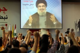 Supporters of Hassan Nasrallah (portrait), the head of Lebanon's militant Shiite Muslim movement Hezbollah raise their fists as they watch him giving a televised address in Beirut on June 14, 2013