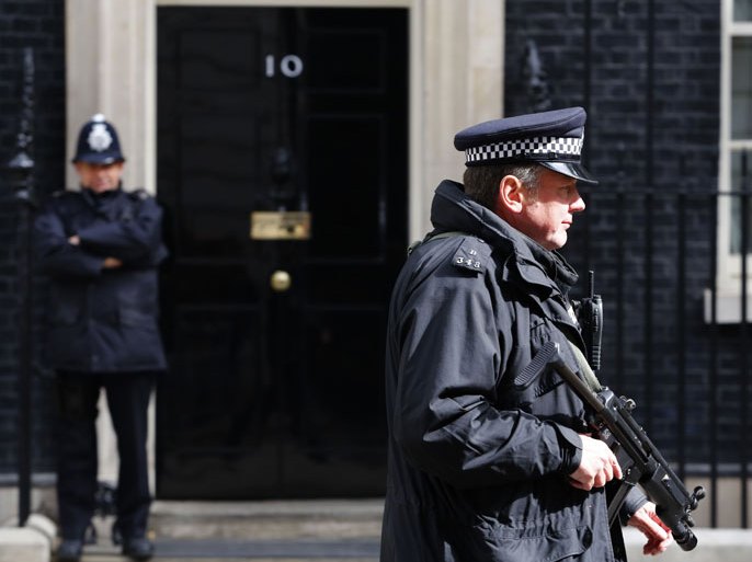 epa03713174 An armed British police office outside the British Prime Minister's London residence 10 Downing Street following a special Cobra meeting in London, Britain, 23 May 2013. Two attackers with kitchen knives killed a British soldier on a street 22 May in south-east London afternoon in a case that police were treating as a suspected terrorist attack. Metropolitan Police Commissioner Sir Bernard Hogan-Howe said officers from the counterterrorist unit were leading the investigation into the 'shocking and horrific' slaying in Woolwich, with two people arrested. EPA/TAL COHEN EPA/TAL COHEN