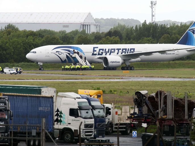 DAN796 - PRESTWICK AIRPORT, -, UNITED KINGDOM : Police escort passengers off the Egyptair Boeing 777 flight from Cairo that was forced to land at Glasgow Prestwick airport in Scotland on June 15, 2013 en route to JFK airport in New York after an onboard incident. Britain's Royal Air Force (RAF) on June 15 escorted an Egyptair plane bound for New York to a Scottish airport following an onboard incident, the Ministry of Defence said. The Boeing 777 was travelling between Cairo and New York when a passenger alerted plane crew that she had found a note reading "I'll set this plane on fire" in the toilet. The message was scrawled in pencil on a napkin and was found by BBC New York producer Nada Tawfik. AFP PHOTO / ANDY BUCHANAN