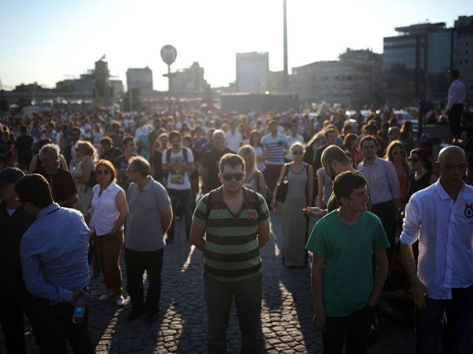 People stand on the flashpoint Taksim square in Istanbul on June 18, 2013 during a wave of new alternative protests. Prime Minister Recep Tayyip Erdogan on June 18 claimed victory over Turkey's anti-government protesters after a heavy crackdown on the movement, as police raided homes and arrested dozens of demonstrators to stamp out nearly three weeks of unrest. In Istanbul, dozens of demonstrators switched to silent protests, standing still in quiet defiance in the main Taksim Square located next to the Gezi Park. AFP