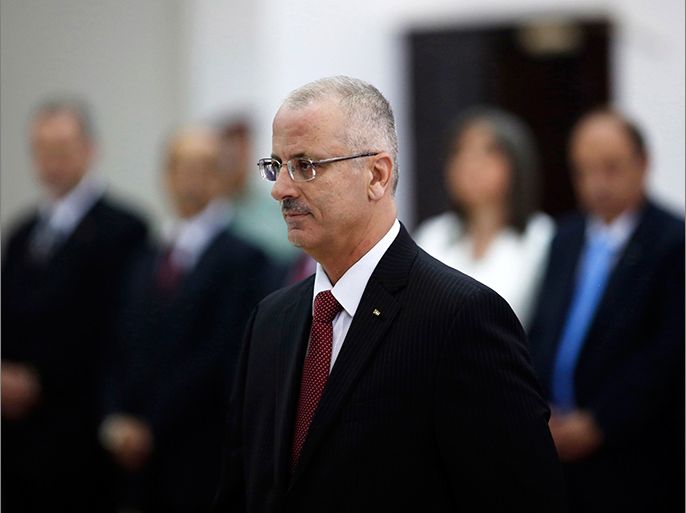 Palestinian Prime Minister Rami Hamdallah (C) stands during a swearing-in ceremony of the new government in the West Bank city of Ramallah June 6, 2013. Hamdallah and his West Bank-based government were sworn in on Thursday and one of their main challenges will be reaching a power-sharing deal with the Islamist Hamas movement ruling Gaza. REUTERS/Mohamad Torokman (WEST BANK - Tags: POLITICS)