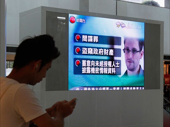 A man checks his mobile phone in front of a monitor broadcasting news on U.S. charges against Edward Snowden, a former contractor at the National Security Agency (NSA), at a shopping mall in Hong Kong June 22, 2013. The United States has filed espionage charges against Snowden, who admitted revealing secret surveillance programs to media outlets, according to a court document made public on Friday. REUTERS/Bobby Yip (CHINA - Tags: POLITICS CRIME LAW SCIENCE TECHNOLOGY)