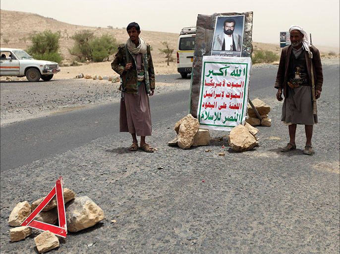 Followers of Yemen's al-Houthi Shi'ite group stand next to the image of al-Houthi Hussein Badr Eddin al-Huthi, the late founder of the group, in front of the entrance to the city ahead of Huthi's funeral in the northwestern province of Saada June 4, 2013. The body of Huthi, who was killed in clashes with government forces in 2004, was released by Yemeni authorities nine years after his death following which DNA tests were carried out to determine his identity, local media reported. REUTERS/Mohamed al-Sayaghi (YEMEN - Tags: RELIGION POLITICS CIVIL UNREST)