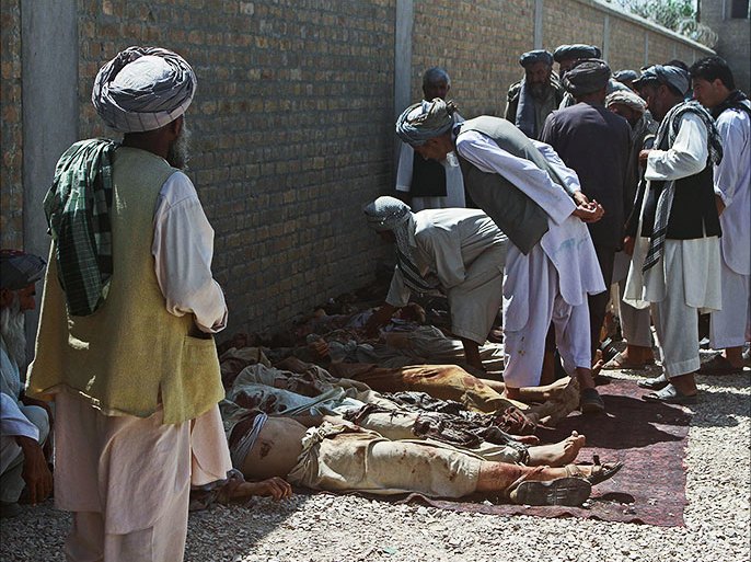 Afghan men attempt to identify the bodies of Taliban fighters on the premises of a police station after an operation in Qala-e Zal district of Kunduz province on June 22, 2013. Eighteen Taliban fighters were killed and eleven more wounded in the operation, officials said. AFP PHOTO/ABULMOTALEB
