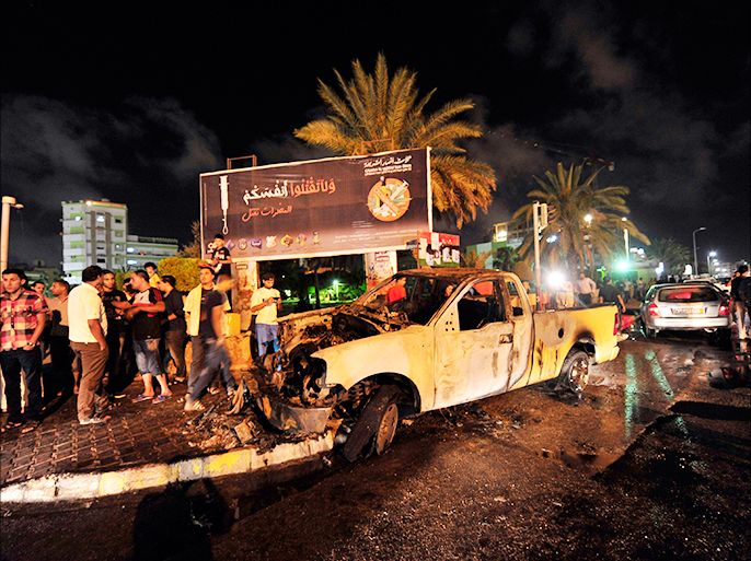 People gather around a burnt-out vehicle used by the Libyan Army's First Infantry Brigade, one of two military vehicles set on fire by protesters, in Benghazi June 14, 2013. The protesters said they had burnt the vehicles, both of which belonged to the Libyan Army's First Infantry Brigade, as they accused the brigade of being responsible for clashes that broke out at the headquarters of the Libya Shield militia last week. No people were injured during the fires, according to the demonstrators. REUTERS/Esam Al-Fetori (LIBYA - Tags: MILITARY CIVIL UNREST)