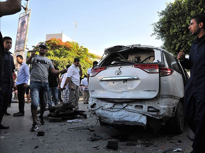 Members of security and civilians gather near an Italian diplomatic car after experts detonated a bomb that was discovered planted underneath it, in Tripoli June 11, 2013. The driver of the car discovered the explosive device when he stopped the vehicle after hearing a strange noise, a ministry spokesman told Reuters. Two embassy officials were travelling in the car. No one was injured. REUTERS/Stringer (LIBYA - Tags: POLITICS CIVIL UNREST)