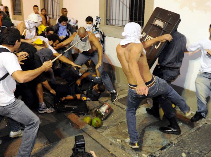 Rio de Janeiro, -, BRAZIL : Demonstrators clash with riot police during a protest in front of Rio de Janeiro's Legislative Assembly (ALERJ) building in Rio de Janeiro, on June 17, 2013. Tens of thousands of people took to the streets of major Brazilian cities protesting the billions of dollars spent on the Confederations Cup --and preparations for the upcoming World Cup-- and against the hike in mass transit fares. AFP PHOTO / TASSO MARCELO