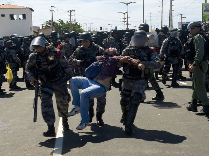 Anti-riot police officers carry a wounded demonstrator after clashes erupted in Fortaleza, Northern Brazil, on June 19, 2013 during a protest of what is now called the 'Tropical Spring' against corruption and price hikes. In a country with one of the widest income disparities in the world -- billions of dollars were being spent on stadiums and little on social programs - and the Confederations Cup football tournament going on, Brazil has two weeks to convince sceptics that it can honour its pledge to stage a successful World Cup in 2014. AFP PHOTO / YURI CORTEZ