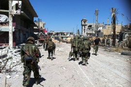 army's soldiers walk in a street left in ruins on June 5, 2013 in the city of Qusayr in Syria's central Homs province, after the Syrian government forces seized total control of the city and the surrounding region. The Syrian army ousted rebels from the strategic town of Qusayr after a blistering 17-day assault led by Hezbollah fighters, scoring a major battlefield success in a war that has killed at least 94,000 people. AFP PHOTO / STR