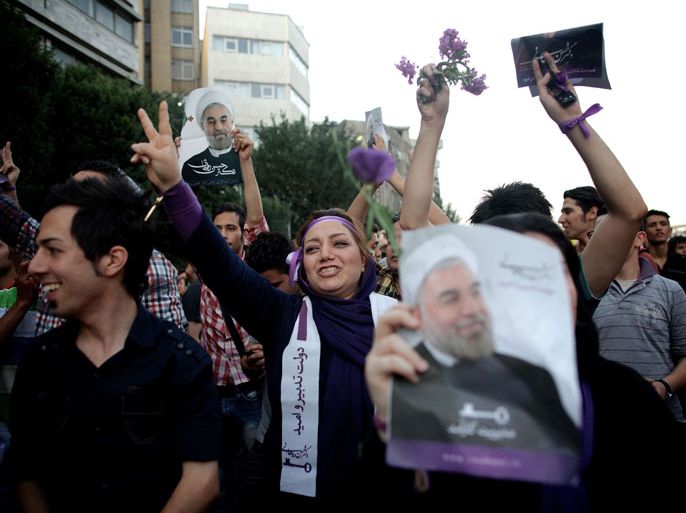 Iranian supporters of moderate presidential candidate Hassan Rowhani hold his portrait as they celebrate his victory in downtown Tehran, on June 15, 2013. Iran's supreme leader Ayatollah Ali Khamenei congratulated Rowhani on winning the presidential election, the website leader.ir reported. AFP PHOTO/BEHROUZ MEHRI