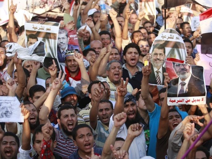 Supporters of Egypt's ousted President Mohammed Morsi wave Egyptian flags and posters with his pictures during a rally near Cairo University in Giza, Egypt, Sunday, July 7, 2013. Feuding erupted within Egypt's new leadership on Sunday as secular and liberal factions wrangled with ultraconservative Islamists who rejected their choice for prime minister, stalling the formation of a new government after the military's ouster of President Mohammed Morsi. The Arabic words on the posters read, "No alternative to legitimacy."