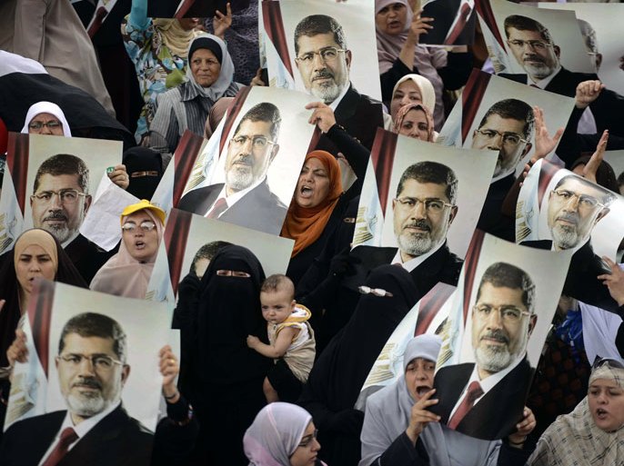 Female Egyptian supporters of the Muslim Brotherhood hold up portraits of Egypt's ousted president Mohamed Morsi during a rally in Cairo on July 21, 2013. Supporters of Morsi, who has been held in custody since his ouster on July 3, view the army's decision to overthrow the man they voted into power last year as an affront to democracy