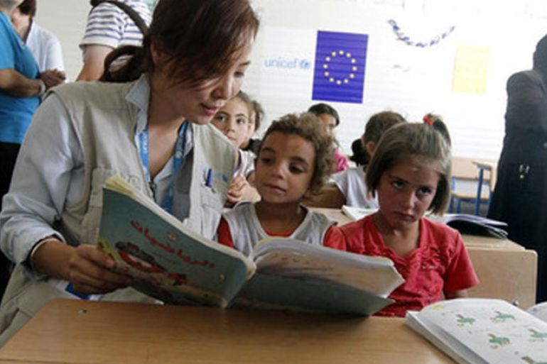 epa03730777 A UNICEF official (L) reads for Syrian refugee students at a school for Syrian refugees at Zattari camp near the city of Mafraq, Jordan, 04 June 2013. European Union Commissioner for Enlargement and European Neighborhood Policy Stefan Fule inaugurated the second school financed by the European Commission through UNICEF at the refugee camp. Commissioner Fule on 03 June announced an additional 50 million Euros of assistance to Jordan to alleviate the impact of the high influx of refugees from Syria, bringing the total amount of financial assistance provided by the European Commission to Jordan in relation to the Syrian crisis to 137 million euros since its outbreak