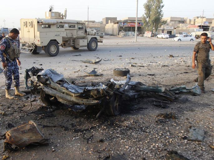 MI03 - Kirkuk, -, IRAQ : An Iraqi soldier (L) inspects the wreck of a car bomb after it exploded in the military zone of the northern Iraqi city of Kirkuk on July 11, 2013. Militants killed 25 Iraqi security forces members in a wave of attacks and 15 people died in other attacks, including 10 in twin bombings targeting mourners, officials said. AFP PHOTO MARWAN IBRAHIM