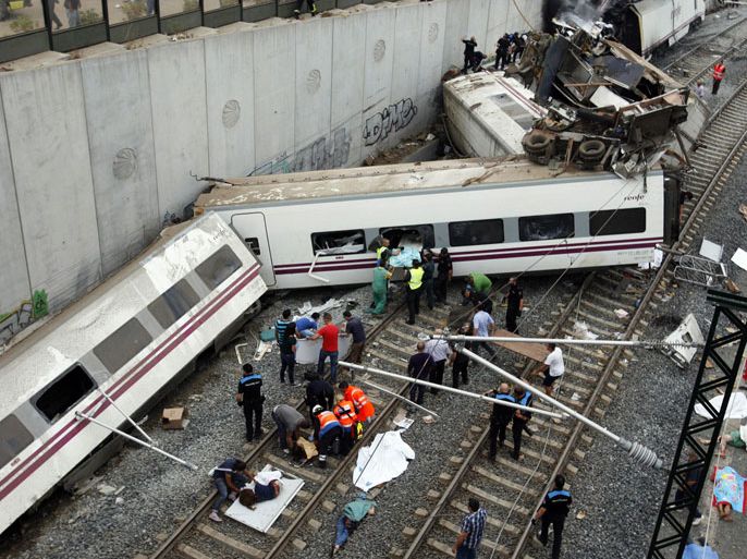 Rescuers tend to victims next to derailed cars at the site of a train accident near the city of Santiago de Compostela on July 24, 2013. Between 45 and 50 people died when a train derailed in Galicia in northwestern Spain today, the president of the regional government of Galicia said. The train which carried 238 passengers originated in Madrid and was bound for the northwestern town of Ferrol. AFP PHOTO / OSCAR CORRAL