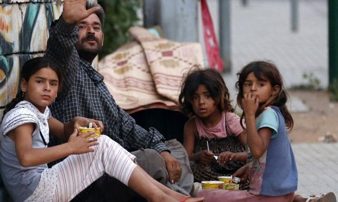 A homeless Syrian man and his children sit along a street in Beirut July 22, 2013. The United Nations Children's Fund (UNICEF) said as many as 800,000 Syrian children are missing out on education because of the country's civil war.